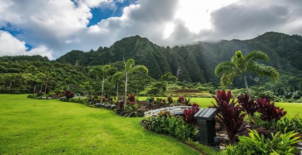 A memorial garden with red ti plants and lawn at Valley of the Temples
